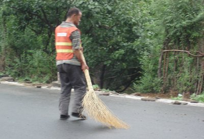 Chinese worker sweeping the highway.
